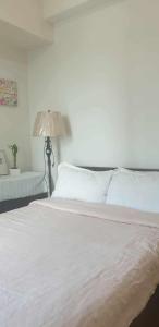 a bedroom with a large white bed with a lamp at 8 Adriatico Condotel Unit Facing Manila Bay in Manila
