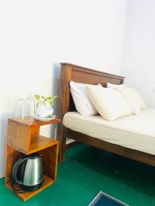 a bedroom with two beds and a side table with a tea kettle at Cinty Guest House in Dambulla