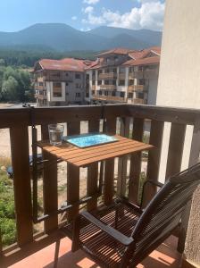 een tafel en een stoel op een balkon met uitzicht bij Cozy Mountain View Apartment with Balcony & Ski Access nearby - Serendipity in Bansko