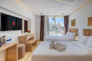 una camera d'albergo con due letti e una tv di The Platinum Pyramid view inn a Il Cairo