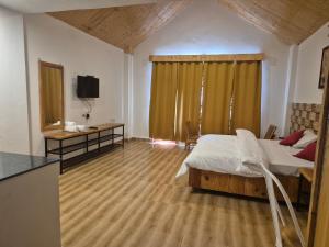 Un dormitorio con una cama, un escritorio y un televisor. en Rustic Retreat, en Manali