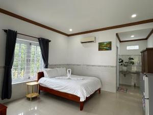 a bedroom with a bed with white sheets and a window at I Hostel Muine - A Little White Homestay By The Sea in Mui Ne