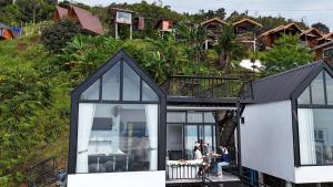 a house on a hill with people sitting on a balcony at เมฆสวรรค์ ภูทับเบิก 2 in Ban Maeo Thap Boek