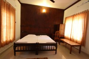 a bedroom with a bed and a bench in it at Raja Park Beach Resort in Varkala