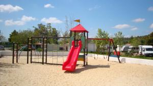 un parque infantil con un tobogán rojo en la arena en Parque de Campismo Orbitur Valverde en Luz