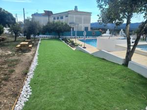 a swimming pool with a green lawn next to a building at Casa de Cardigos in Cardigos