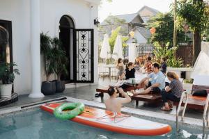 a group of people sitting in a swimming pool with surfboards at Tam Coc Sana Villa & Homestays in Ninh Binh