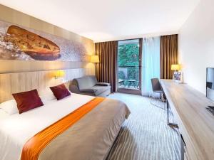 a hotel room with a large bed and a desk at Mercure Gdańsk Posejdon in Gdańsk