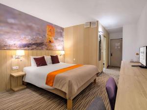 a hotel room with a large bed and a television at Mercure Gdańsk Posejdon in Gdańsk