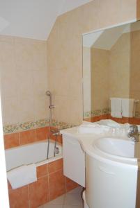 a bathroom with a sink and a tub and a mirror at Hostellerie de la Motte jean in Saint-Coulomb