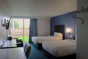 a hotel room with two beds and a window at Travelodge by Wyndham Milwaukee in Milwaukee