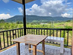 a wooden table and bench on a balcony with mountains at บ้านสวนหมอกเขาค้อ b1 in Khao Kho