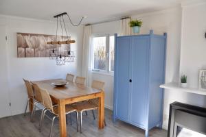 a dining room with a table and a blue cabinet at Chalet Christine in Petten +4 photos