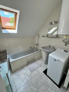 a white bathroom with a tub and a sink at Nyugalom Szigete Apartmanok in Harkány +62 photos