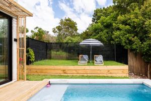 a backyard with a pool and two chairs and an umbrella at SALT Luxury Guest Suite Plett in Plettenberg Bay +4 photos