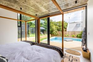 a bedroom with a large window and a swimming pool at SALT Luxury Guest Suite Plett in Plettenberg Bay