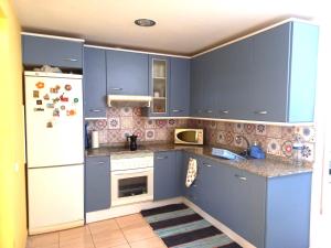 a kitchen with blue cabinets and a white refrigerator at MELROSE PLACE 2 Dormitorios y Piscina en Vecindario in Vecindario
