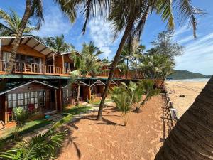 a resort on the beach with palm trees at Jardim a Mar in Agonda