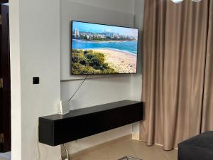 TV de pantalla plana colgada en la pared de la sala de estar. en Duplex cornish lac2, en Túnez
