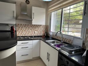 Una cocina con gabinetes blancos y un fregadero y una ventana. en Duplex cornish lac2, en Túnez