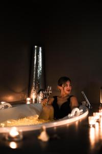 a woman sitting in a bath tub with a glass of wine at Lido Palace - The Leading Hotels of the World in Riva del Garda