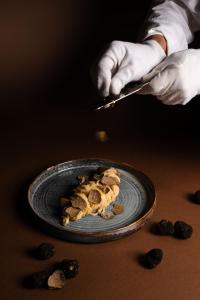 a person holding a knife and a plate of food at Lido Palace - The Leading Hotels of the World in Riva del Garda