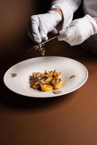 a person cutting a plate of food on a table at Lido Palace - The Leading Hotels of the World in Riva del Garda