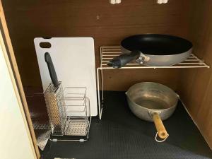a kitchen with a pan and a bowl on a shelf at 完全プライベートルーム 東京 府中駅徒歩圏内 高速フリーWifi キッチン洗濯機完備 二人でも宿泊可 in Fuchu
