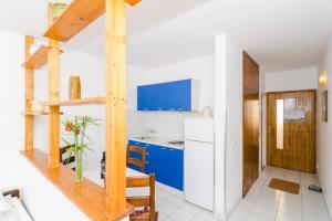 a kitchen with blue cabinets and a table in a room at Apartments Bezek - Studio Apartment with Sea View in Trstenik