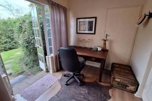 Cette chambre dispose d'une fenêtre et d'un bureau avec une chaise. dans l'établissement Eagle Owl Cottage, à Gqeberha