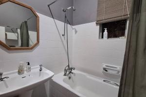 une salle de bain avec un lavabo, une baignoire et une douche dans l'établissement Eagle Owl Cottage, à Gqeberha 38 autres photos