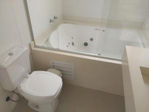 ein weißes Badezimmer mit Toilette und Badewanne in der Unterkunft Casa de Verão no Condomínio Porto Coronado in Xangri-lá