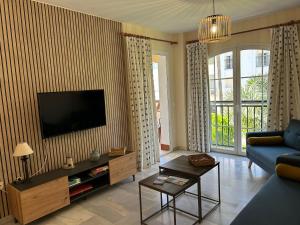 a living room with a blue couch and a tv at HOLIDAYS & HOME II, 3 habitaciones, piscinas ,150 metros playa in Benalmádena