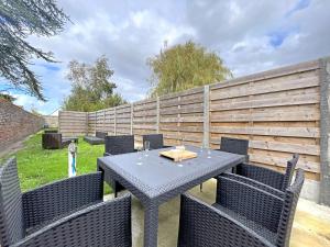 un patio con tavolo, sedie e una recinzione di Maison entre ville et plage avec cour jardin - FR-1-646-78 a Berck-sur-Mer