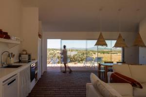 a woman walking through a kitchen and living room with a view at Vagar do Pastor in Alandroal