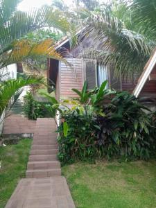 a house with palm trees and a walkway at Pousada Mon Desir in Penedo