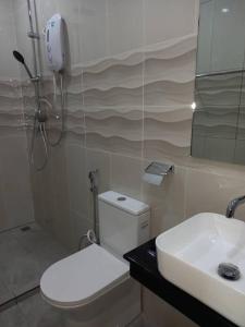 a bathroom with a white toilet and a sink at Deluxe Room Mandahan Beach Garden in Kimanis