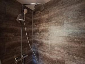 a shower in a bathroom with brown tiles at Pioni Apartment in Pietarsaari +8 photos