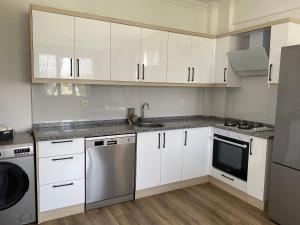 a kitchen with white cabinets and a sink and a dishwasher at Dalaman Çınar Apart in Dalaman