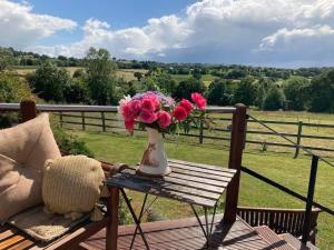 eine Vase mit rosa Blumen auf einem Tisch in der Unterkunft Derbyshire Holiday Cottages in Holmesfield