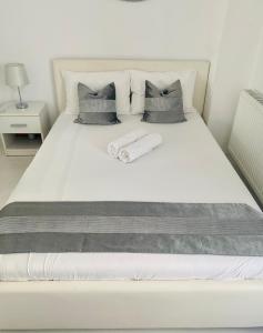 a white bed with two pillows and a towel on it at White Luxury Apartment in Sibiu