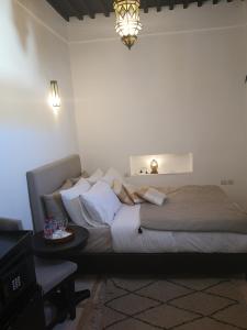 a bedroom with a bed and a table and a lamp at Riad de charme L'Oasis d'Essaouira - Chambre Luxe en Terrasse in Essaouira