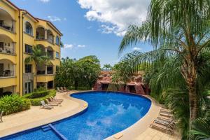 una piscina in un resort con sedie e palme di Sunrise 42 - 2 Bedroom Ocean View Condo a Tamarindo