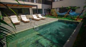 una piscina con sedie a sdraio accanto a un edificio di Blend Coliving AP 312 a Ribeirão Preto