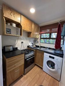 a kitchen with a stove and a washing machine at Khaled Estate Cottages - unit A in Hillcrest +12 photos