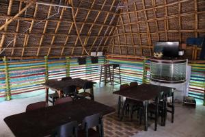 two tables and chairs in a room with a tv at Saikani Beach Resort & Eco stay in Virāmpattinam