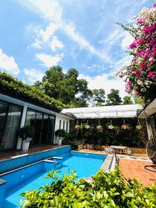 a swimming pool in front of a house with flowers at Đỗ Quyên Villa in Phúc Yên +14 photos
