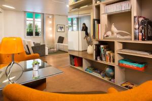 - un salon avec une chaise orange et des étagères dans l'établissement Hôtel Mistral, à Paris