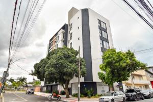 ein hohes weißes Gebäude mit davor geparkt in der Unterkunft Ótima localização, Apto NOVO no Bay Village KQ8551 in Balneário Camboriú