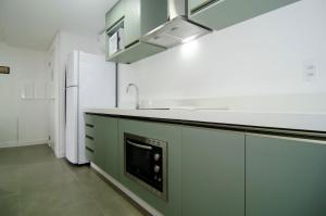 eine Küche mit grünen Schränken, einer Spüle und einem Kühlschrank in der Unterkunft Ótima localização, Apto NOVO no Bay Village KQ8551 in Balneário Camboriú